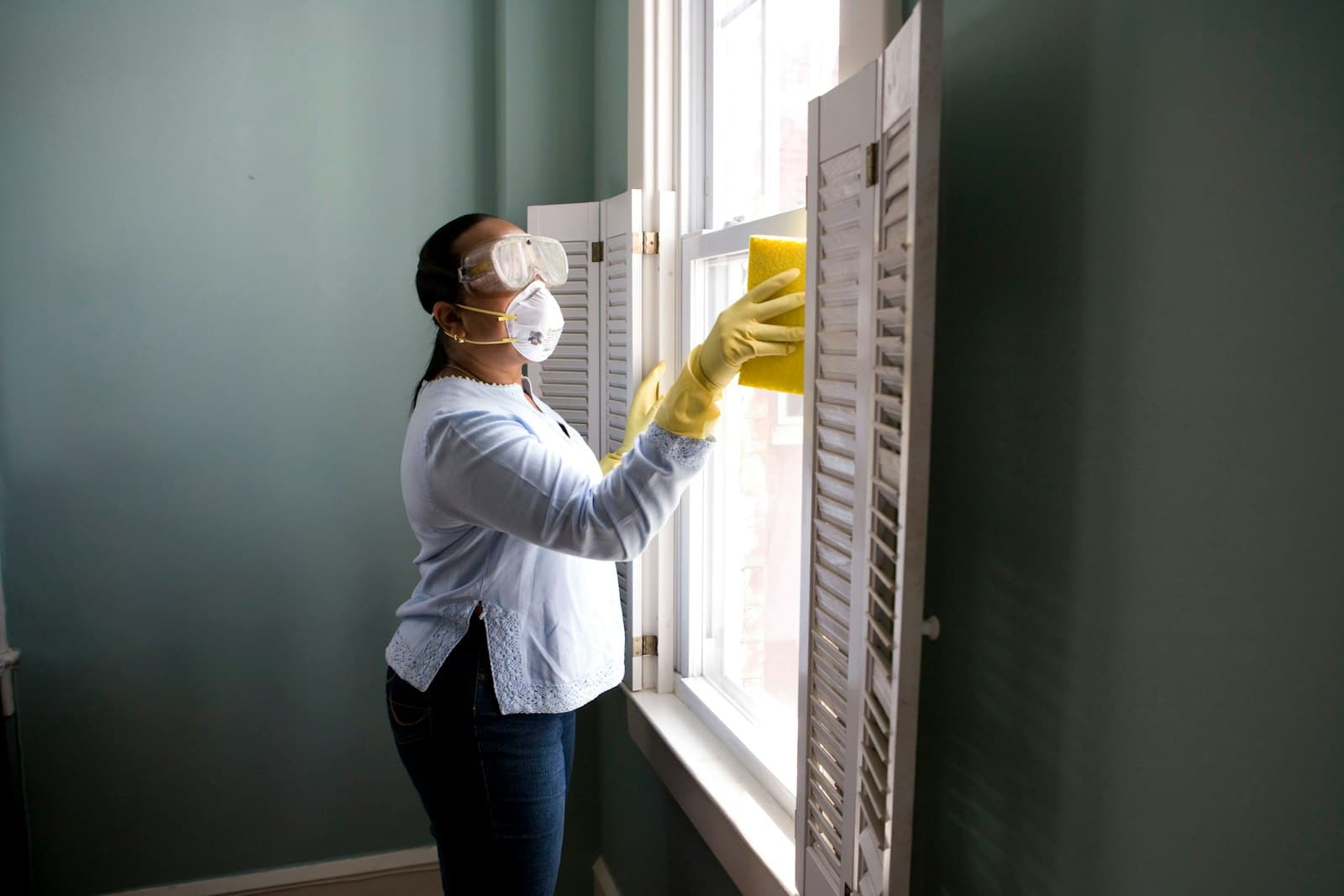 A cleaner wiping down window shutters